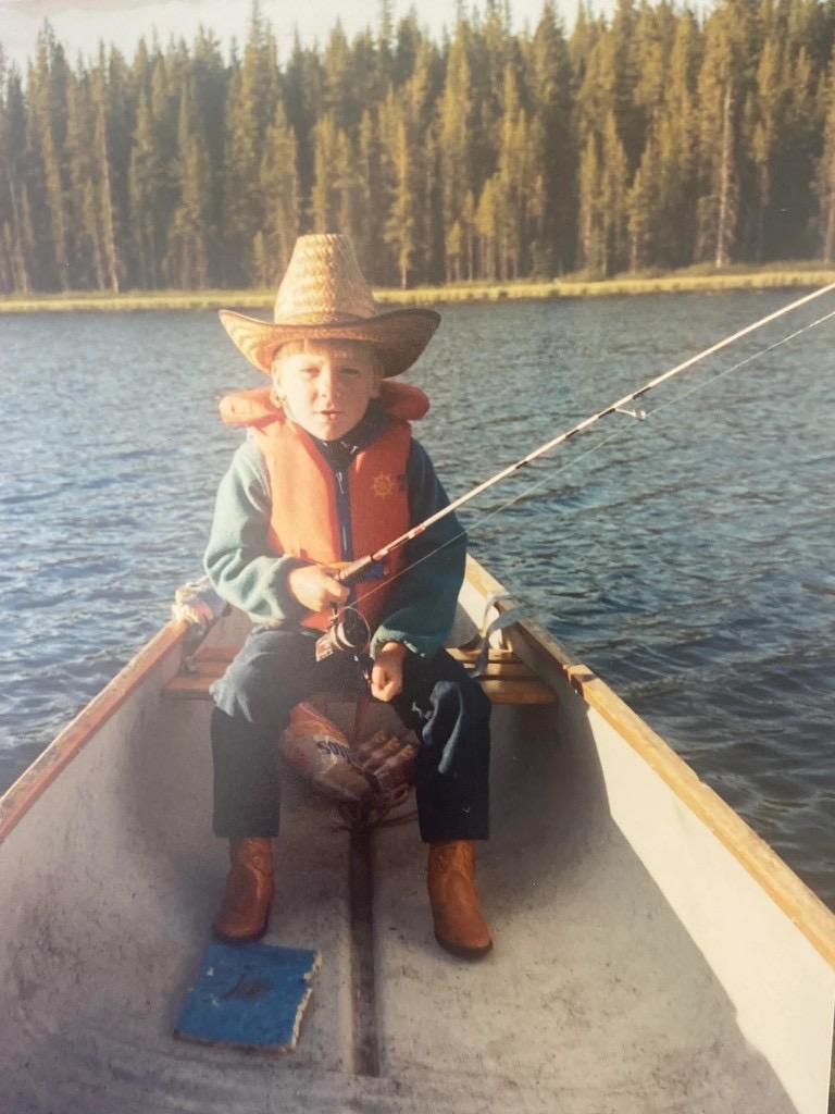Boy in a cowboy hat fishing from a boat