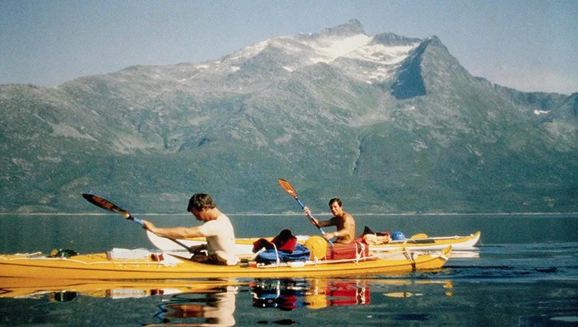 Kayakers on a calm lake under mountains
