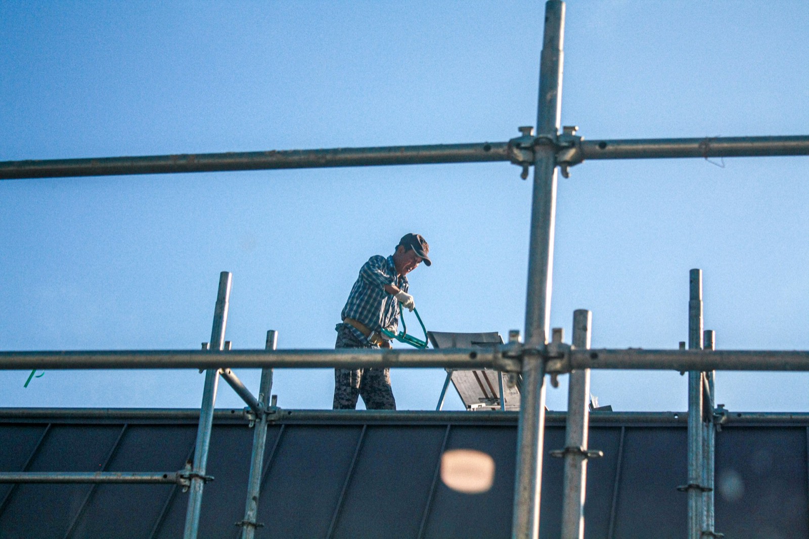 Worker on scaffolding against a blue sky