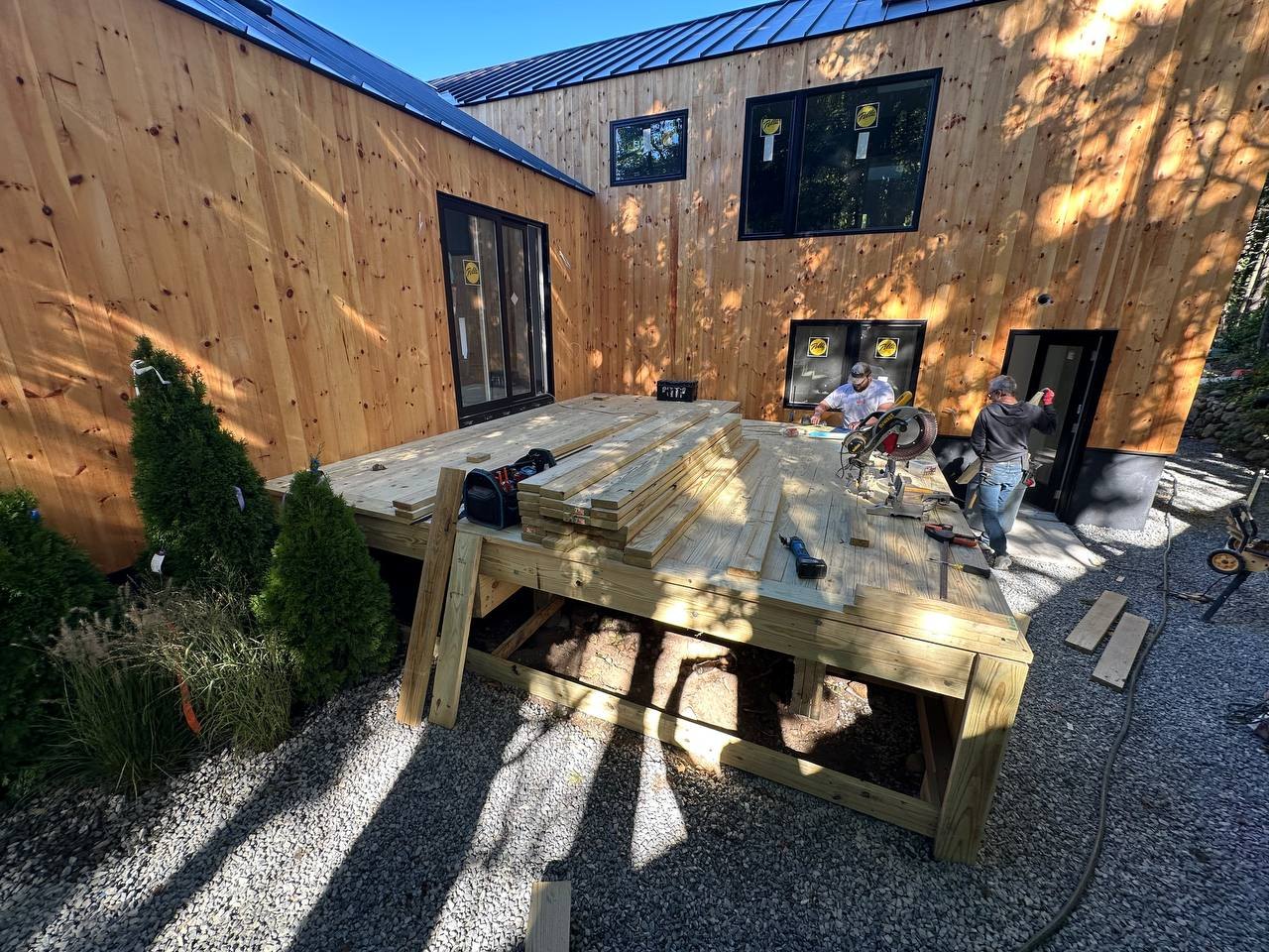 Rear deck under construction between two pine-clad wings