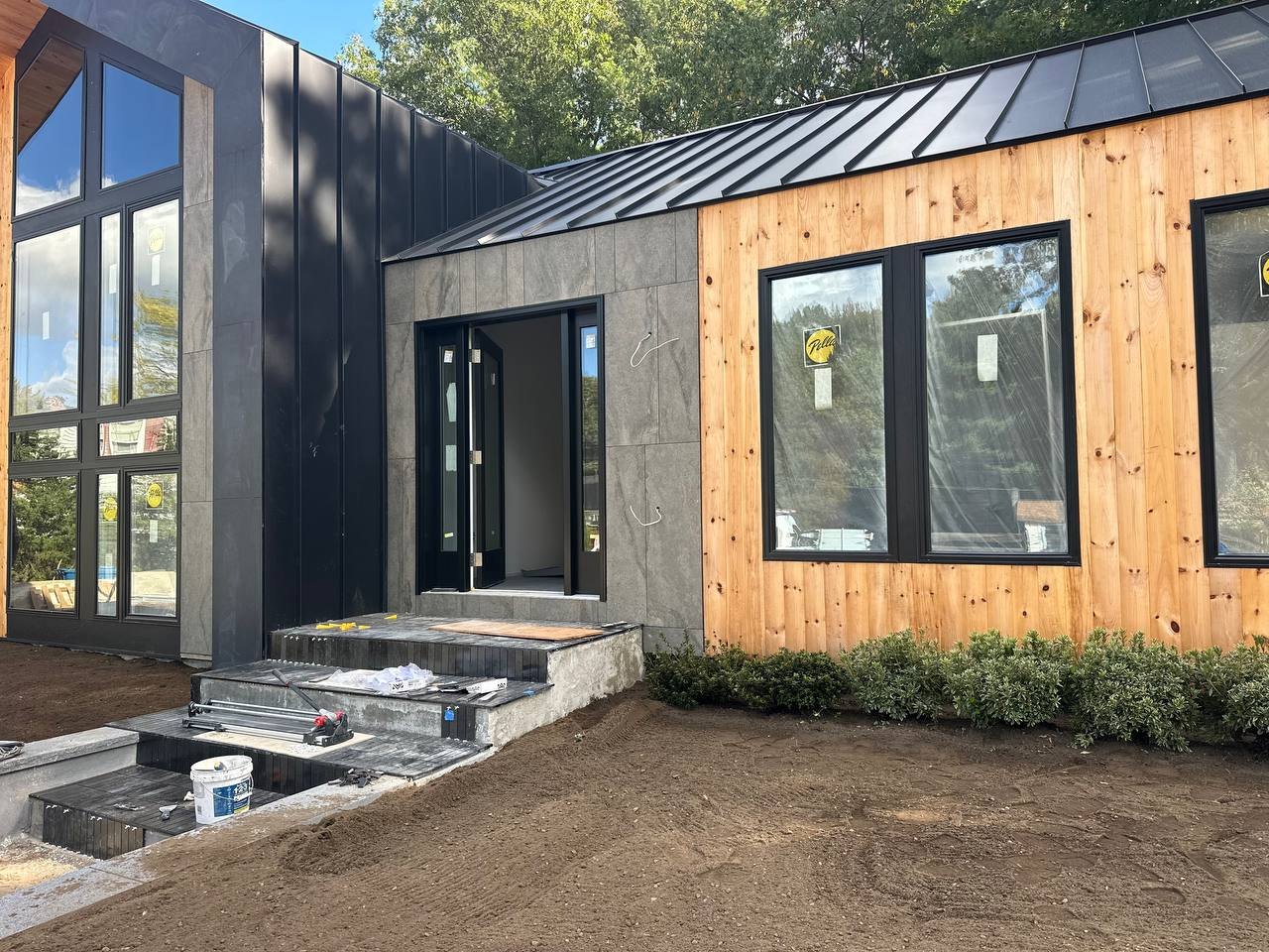 Entry corner with stone panels, black metal, and pine siding