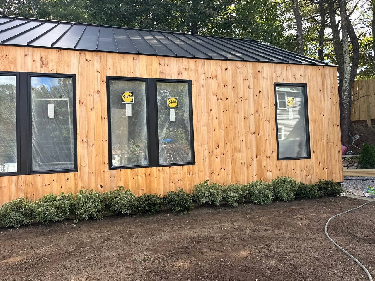 Pine siding, black windows, and a standing-seam metal roof