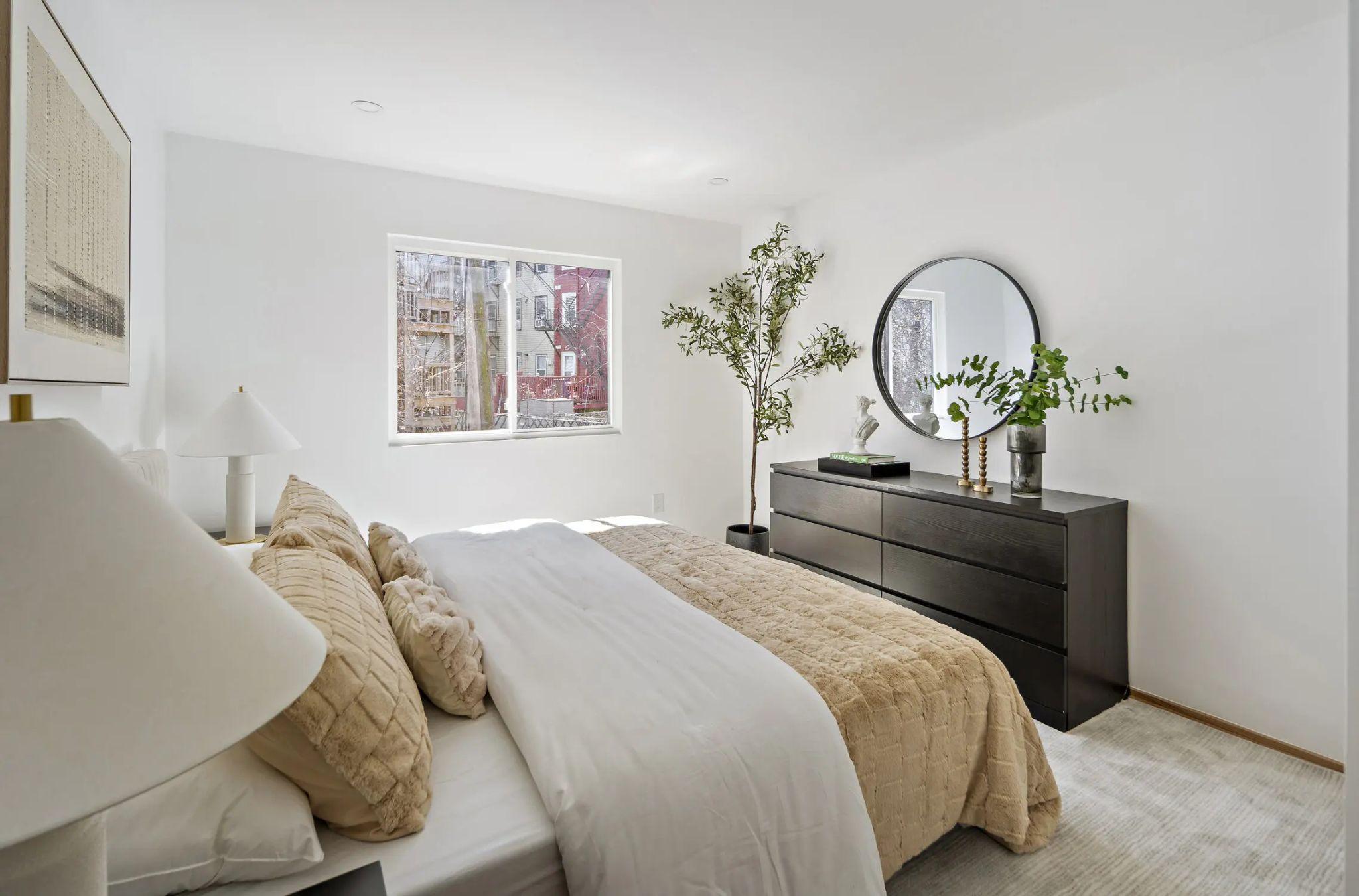 Bedroom with a dark dresser and round mirror