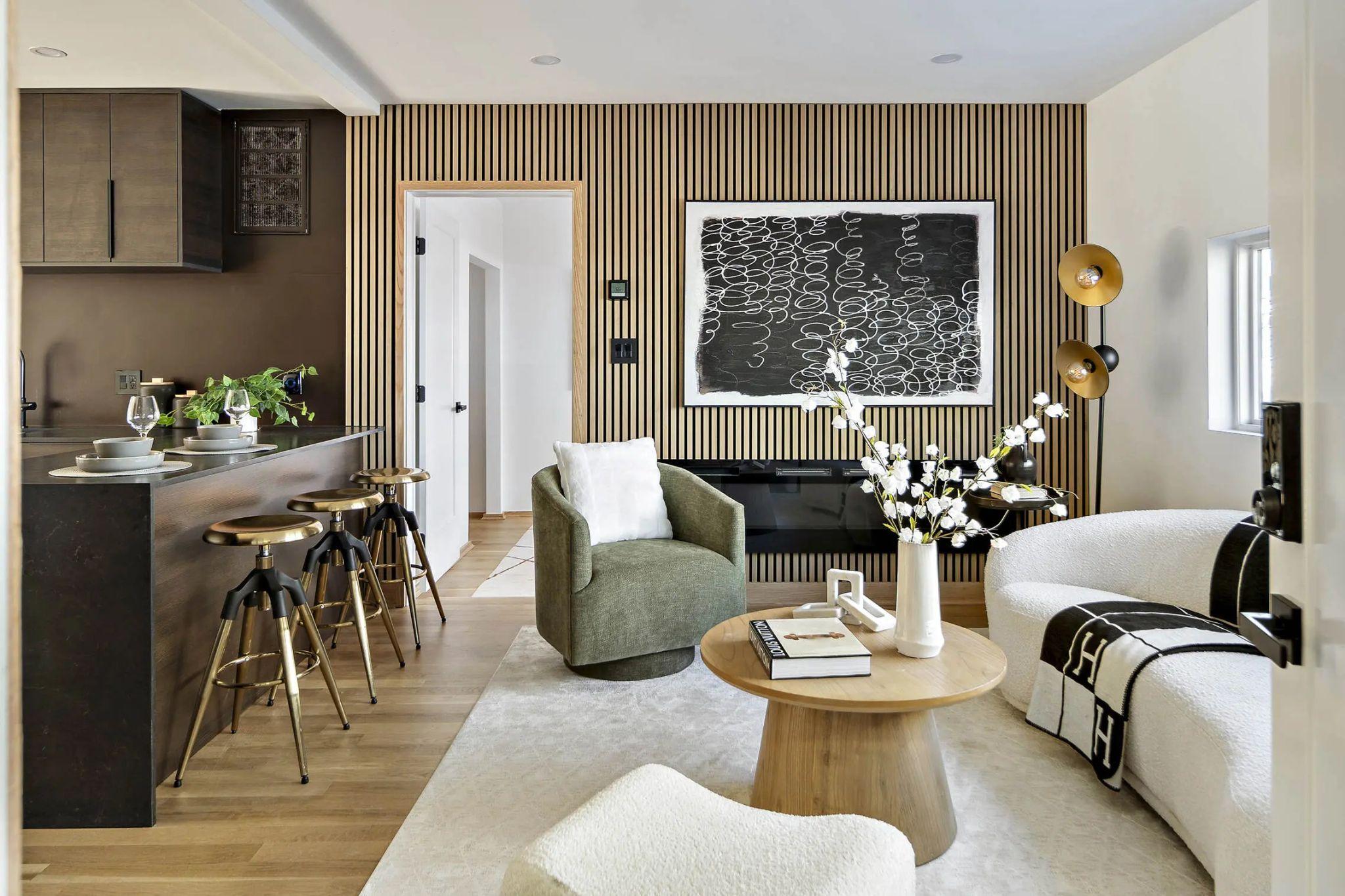 Living room with wood slat wall, green chair, and kitchen bar